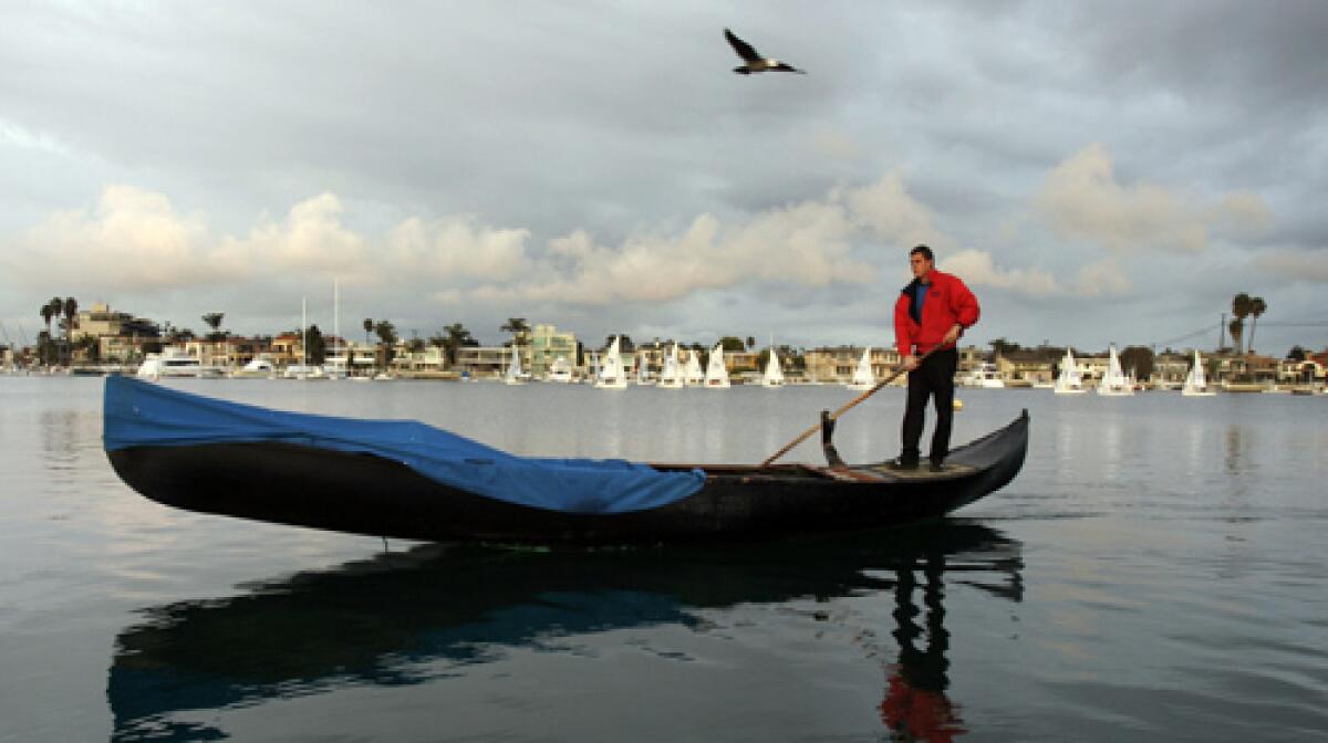 A Gondola Getaway gondolier prepares to take a couple out for a ride in the Belmont Shore neighborhood of Long Beach.