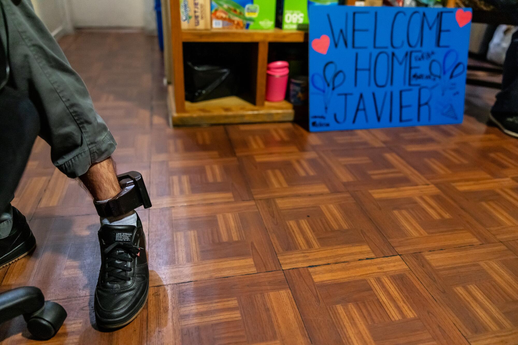 a man wears an ankle monitor in an apartment