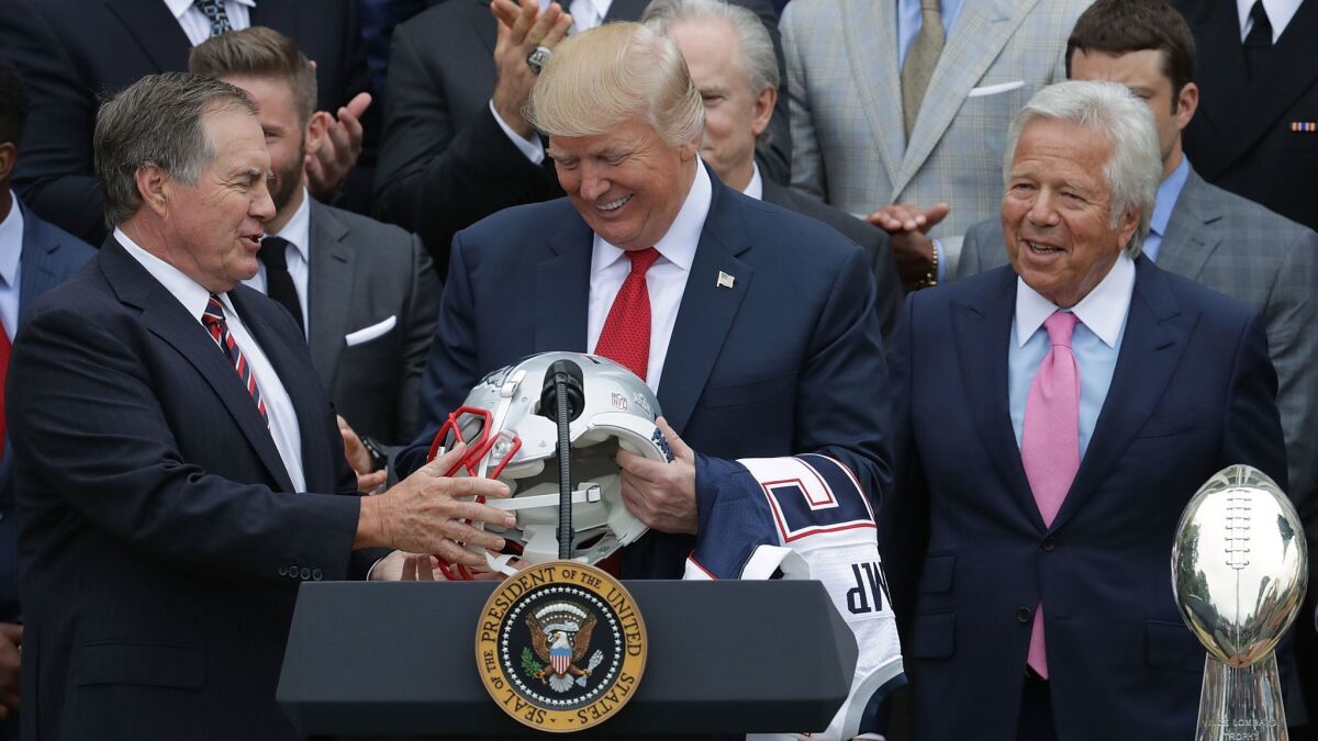 New England Patriots coach Bill Belichick,left, and team owner Robert Kraft present a helmet to President Trump at the White House on April 19, 2017.