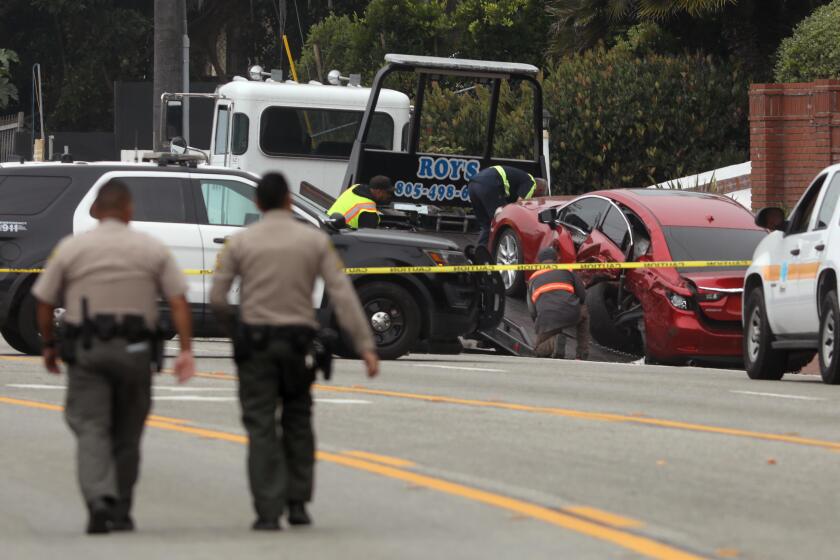 LOS ANGELES, CA - OCTOBER 18, 2023 - Sheriff deputies approach the scene where four women were killed in a multi-vehicle crash in Malibu on October 18, 2023. A 22-year-old man was arrested after plowing into the pedestrians and parked cars. The crash was reported at 8:30 p.m. Tuesday in the 21600 block of Pacific Coast Highway where they found the victims of the crash, along with the severely damaged vehicles. The crash began when the suspect lost control of his BMW and slammed into multiple parked cars before ricocheting and fatally striking the women, who were standing on the side of the road. (Genaro Molina / Los Angeles Times)