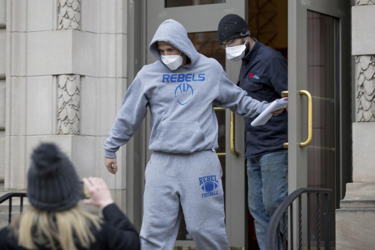 A man in a gray sweatshirt and sweatpants leaves a courthouse