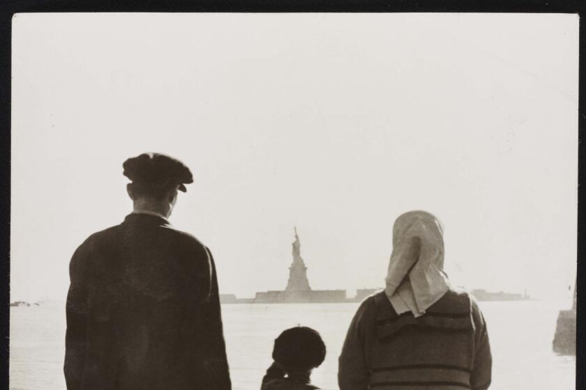 Photo shows immigrant family looking at Statue of Liberty from Ellis Island. c1930