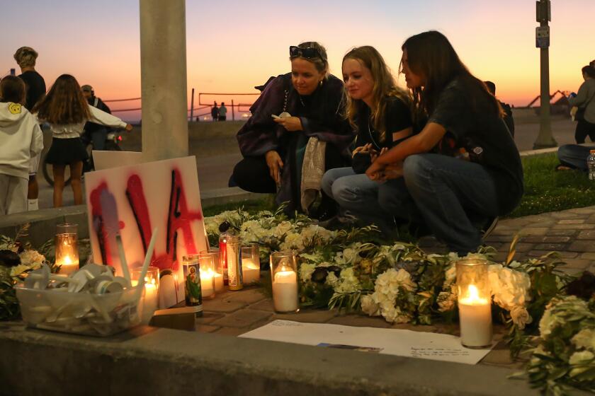 Friends gather at a candlelight shrine in honor of 15-year-old Aayan Randhawa, who went missing while swimming in the ocean off the shores of Huntington Beach on Sunday. The candlelight vigil, held at the Pier Plaza drew over a hundred family and friends who then walked to the end of the pier to throw flowers.