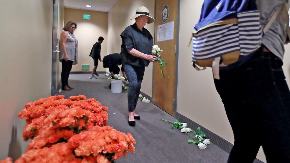 People organized by the group Courage Campaign lay white roses and orange carnations outside Rep. Dana Rohrabacher's office in Huntington Beach on Monday calling for action on gun safety legislation in the wake of the Las Vegas mass shooting Oct. 1.