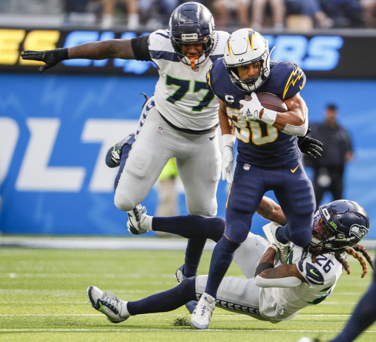 Chargers running back Austin Ekeler is pursued by Seattle's Quinton Jefferson (77) and Ryan Neal.