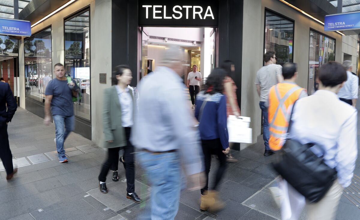Pedestrians walk pas a Telstra store in Sydney, Thursday, May 13, 2021. Telstra, Australia's largest telecommunications company, was fined 50 million Australian dollars ($39 million) for unconscionable conduct in selling remote Indigenous customers mobile phone contracts that they did not understand and could not afford. (AP Photo/Rick Rycroft)