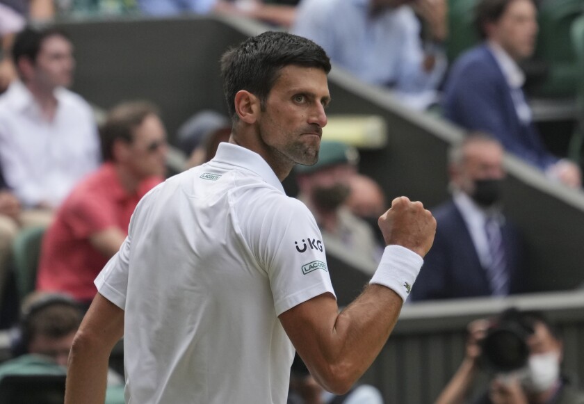 Novak Djokovic makes a fist as he looks over his shoulder.