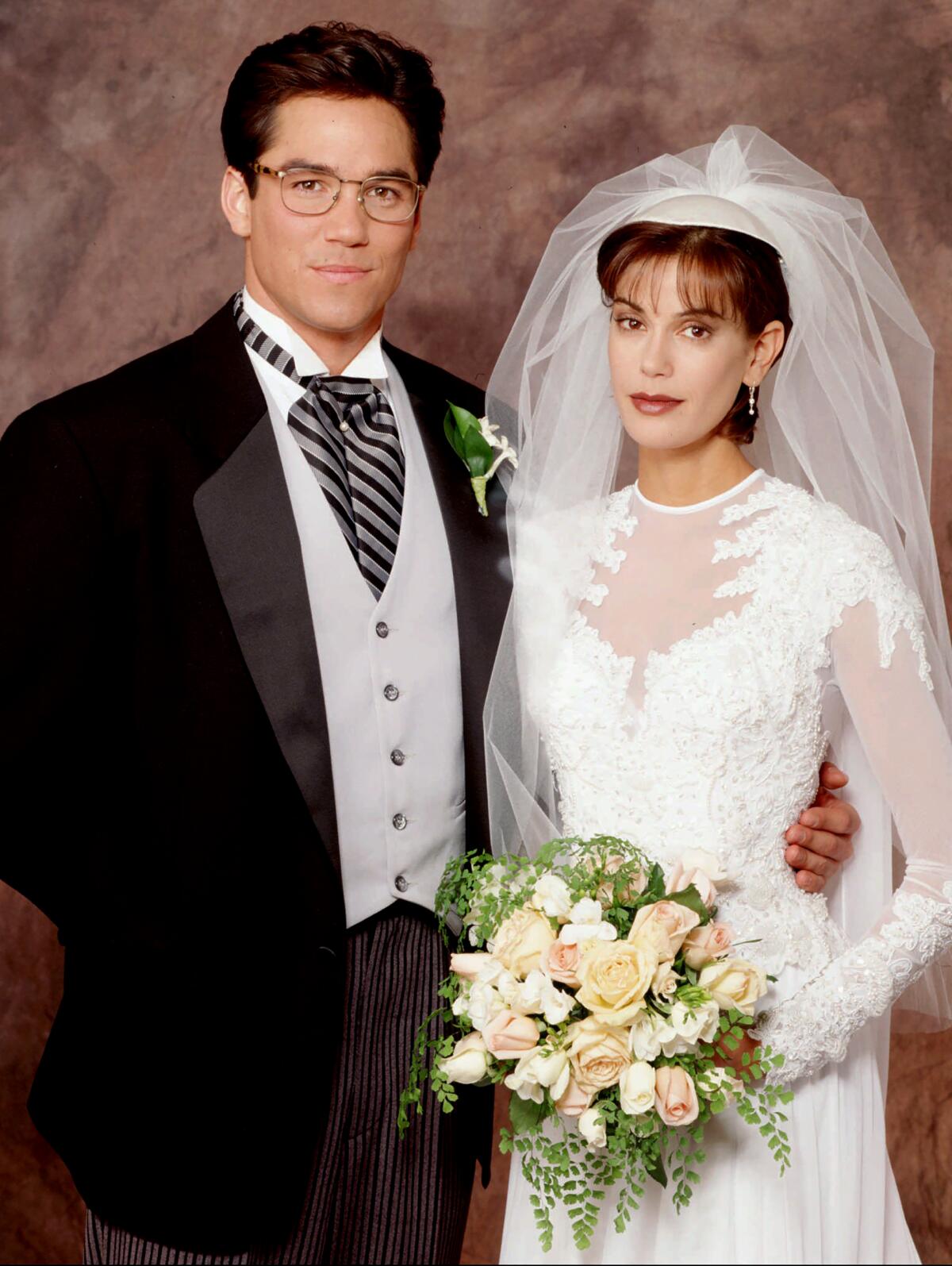 Clark Kent in a tailcoat suit and Lois Lane in a white wedding dress and veil holding a bouquet of flowers.
