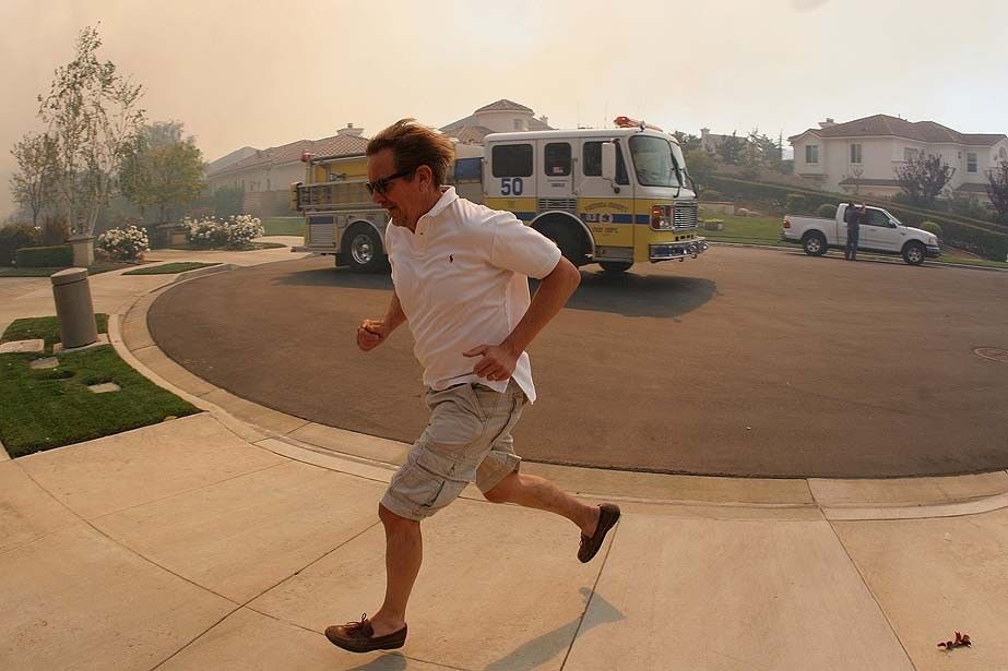 A homeowner in the Dos Vientos neighborhood runs to pack his belongings and flee the approaching Springs fire in Newbury Park.