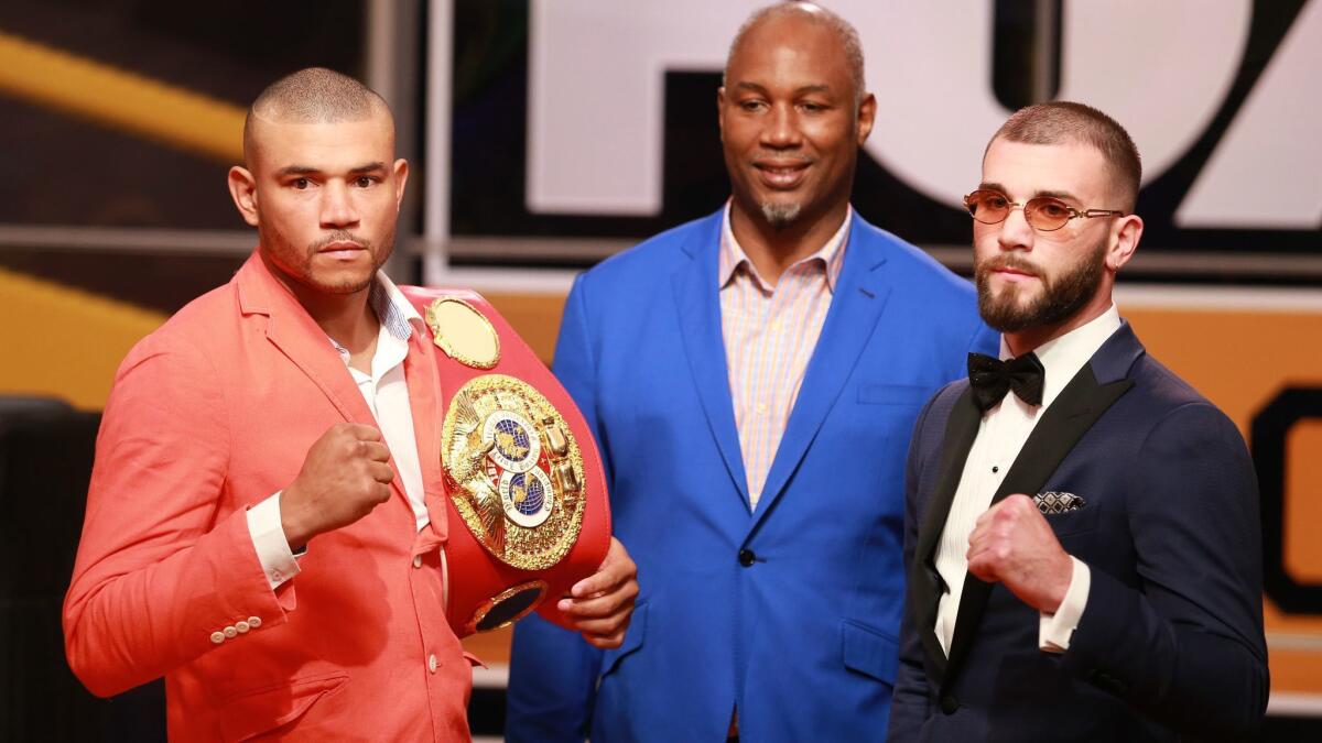 Boxers Jose Uzcategui, left, and Caleb Plant, right flank former heavyweight champion Lennox Lewis during a news conference on Nov. 13 to promote their fight.