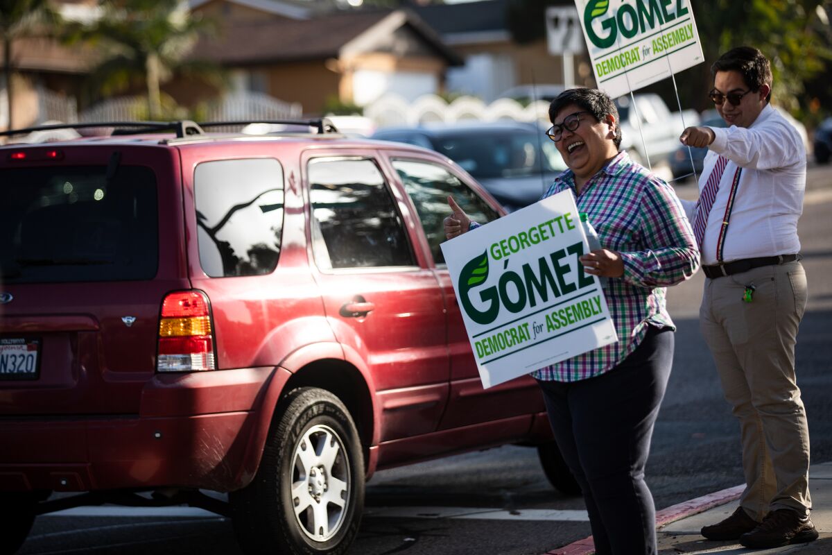 Candidate Georgette Gómez holds a sign and gives a thumbs up to passing motorists on the corner of Telegraph Canyon Road