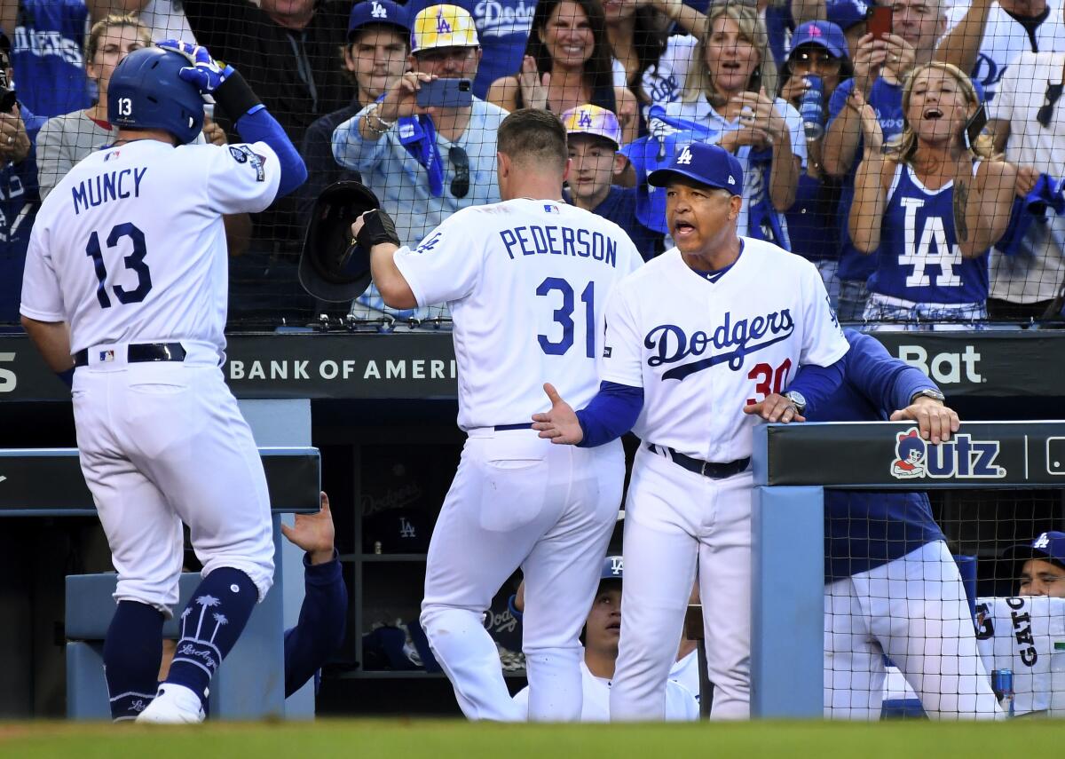 Dodges manager Dave Roberts congratulates Max Muncy after hitting a two-run home run in Game 5 of the NLDS against Washington on Oct. 9, 2019.