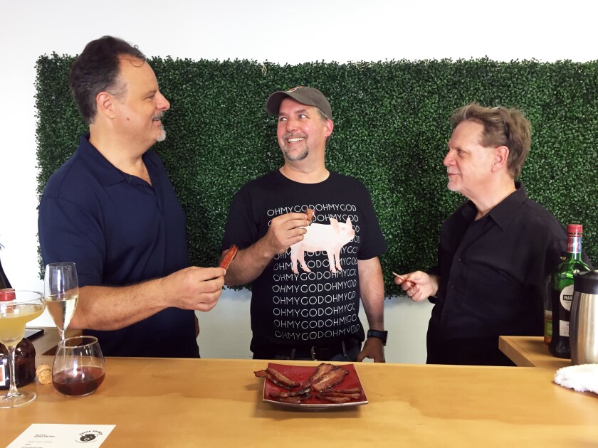 Bacon Swinery founder and "chief swinologist" Curtis McConnell, center, samples some artisan bacon slices with partners Dan Bodenheimer, left, and Bruce Knight.