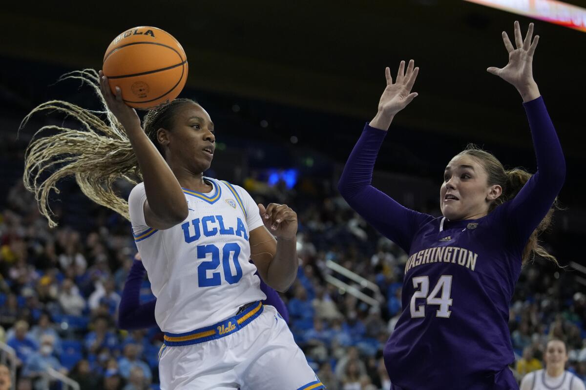 UCLA guard Charisma Osborne, left, passes the ball in front of Washington guard Elle Ladine.