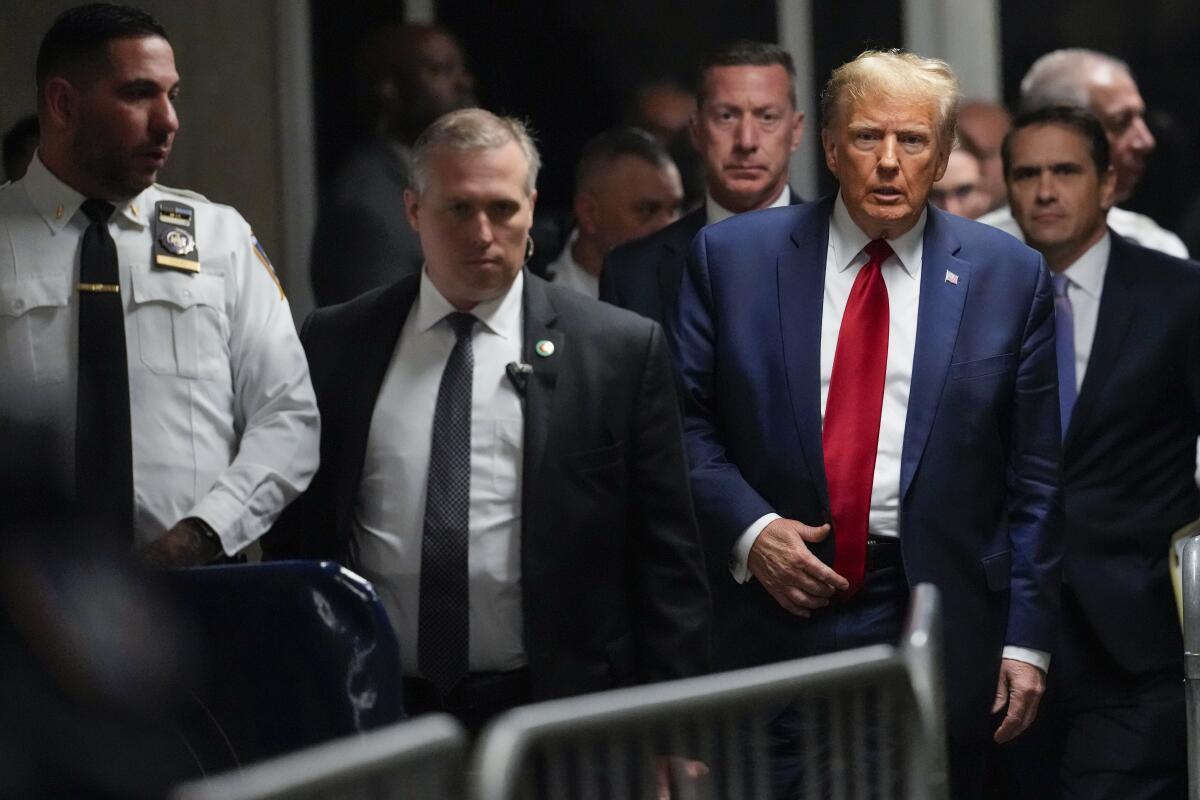 Former President Trump walks alongside a crowd control barrier with other men