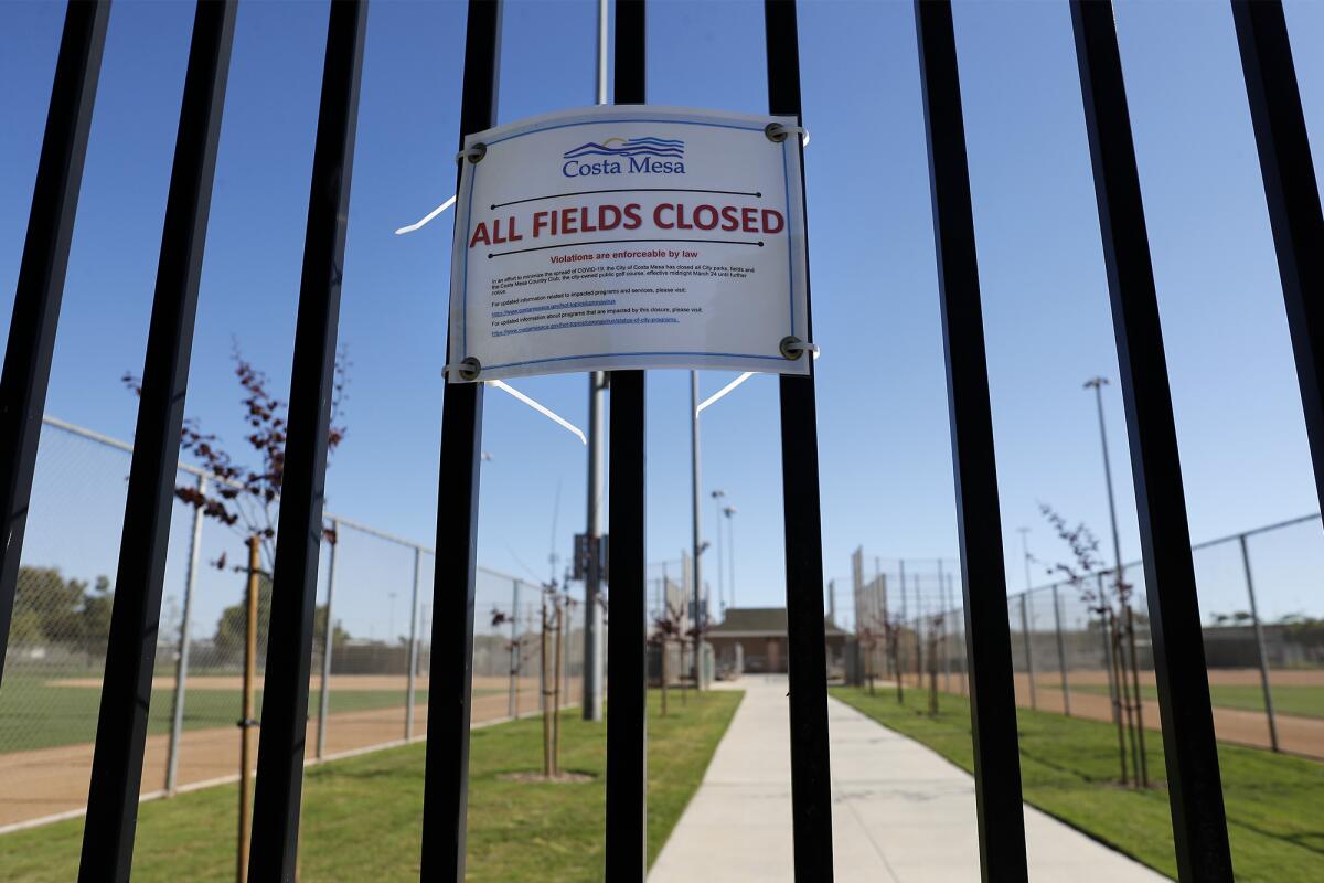 A closure notice is posted on the north gate at TeWinkle Athletic Complex in Costa Mesa on Saturday. Local PONY baseball leagues are sidelined by the coronavirus and are unsure if they will be able to resume play this season.