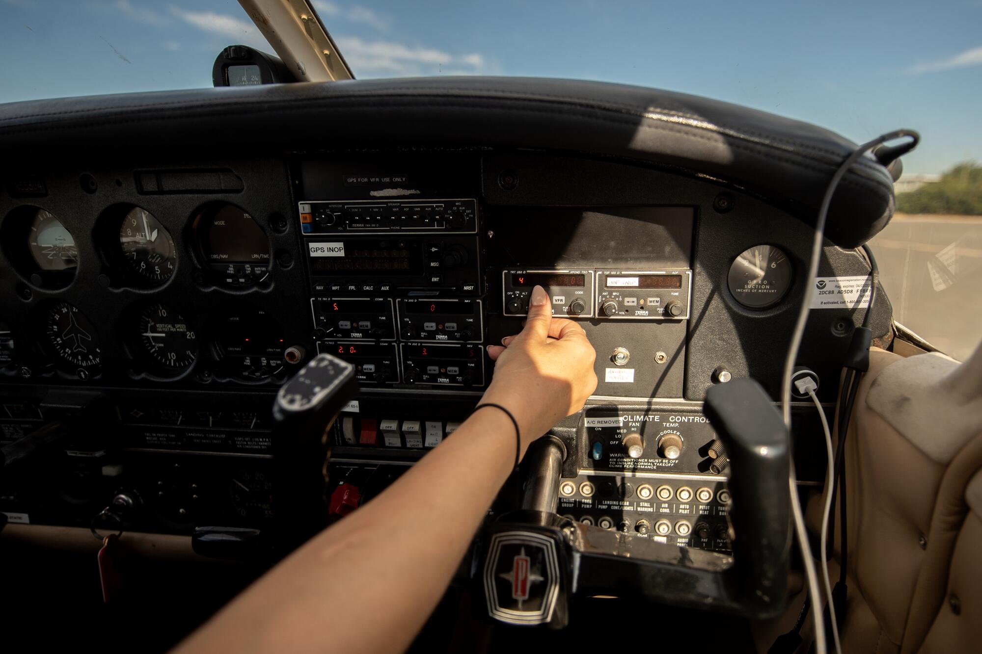 Petra Janney touches a switch on the dashboard of a small plane.
