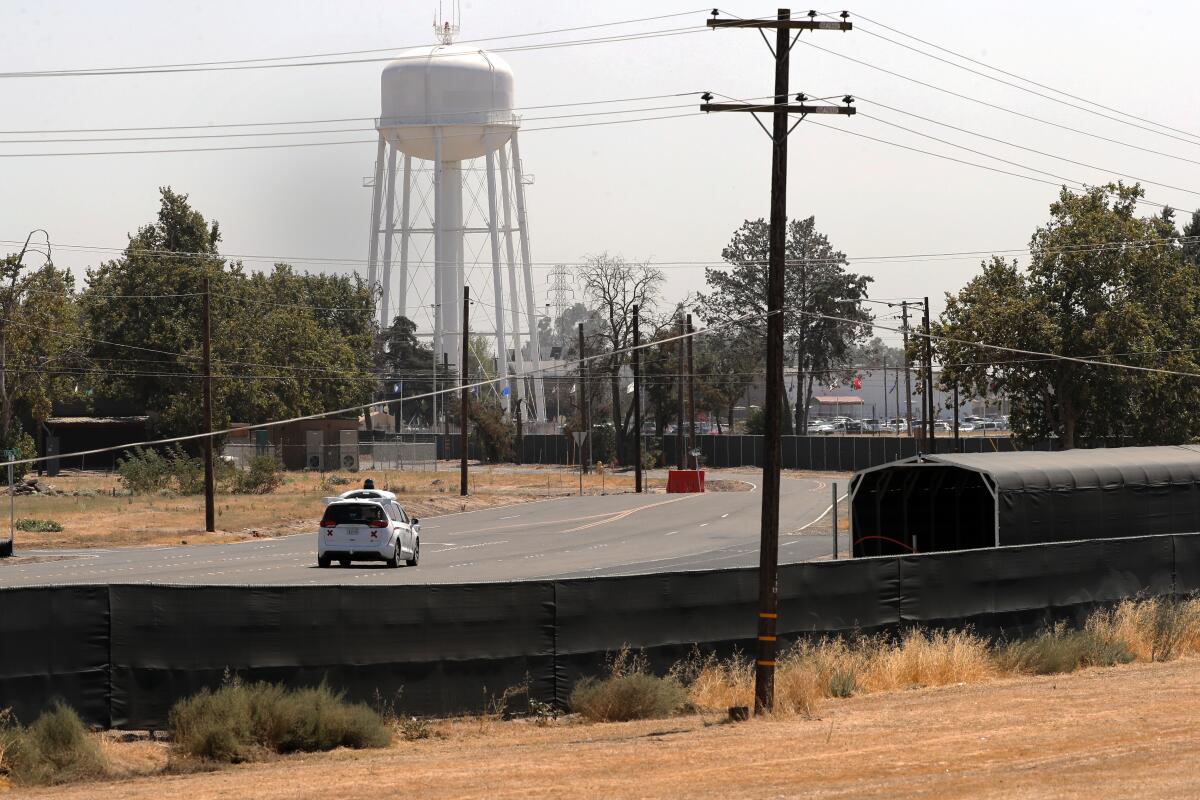 A vehicle heads down a road toward a water tower.