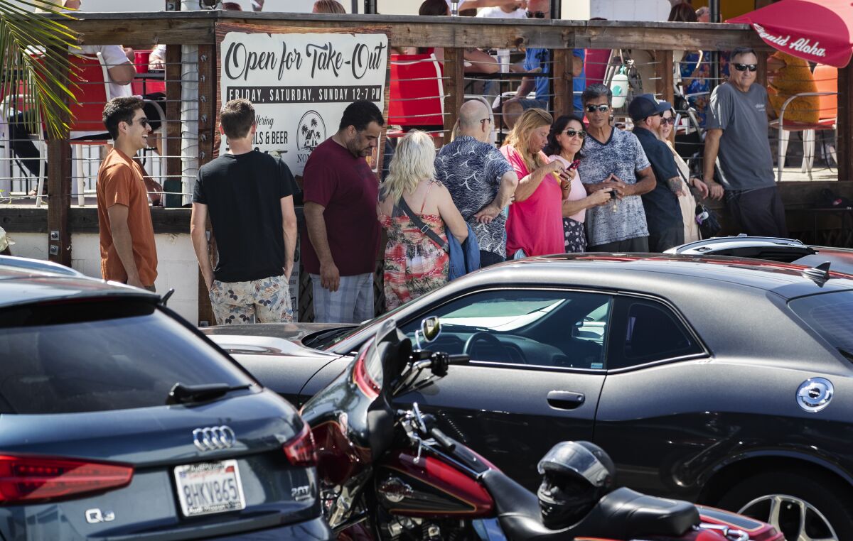 Customers defy social distancing and the wearing of masks to stand in line Thursday at the recently opened Nomads Canteen in San Clemente.