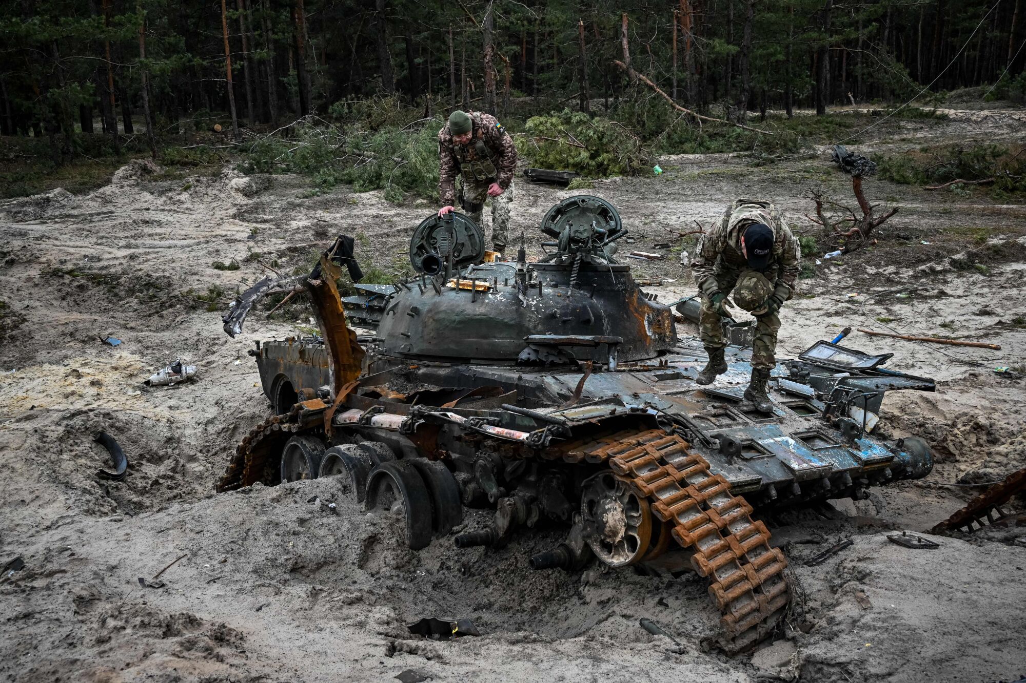 Ukrainian service members inspect a destroyed Russian tank.