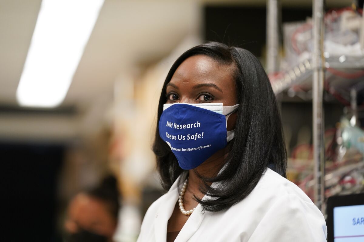 FILE - In this Feb. 11, 2021, file photo, Kizzmekia Corbett, an immunologist with the Vaccine Research Center at the National Institutes of Health (NIH) looks on at the Viral Pathogenesis Laboratory at the NIH in Bethesda, Md. Fewer Americans are reluctant to get a COVID-19 vaccine than just a few months ago, but questions about side effects and how the shots were tested still hold some back, according to a new poll that highlights the challenges at a pivotal moment in the U.S. vaccination campaign. Corbett helped lead development of the Moderna shot, and she spends hours giving plain-spoken answers to questions from Americans — especially Black Americans like her — to counter misinformation about the three vaccines used in the U.S. (AP Photo/Evan Vucci, File)