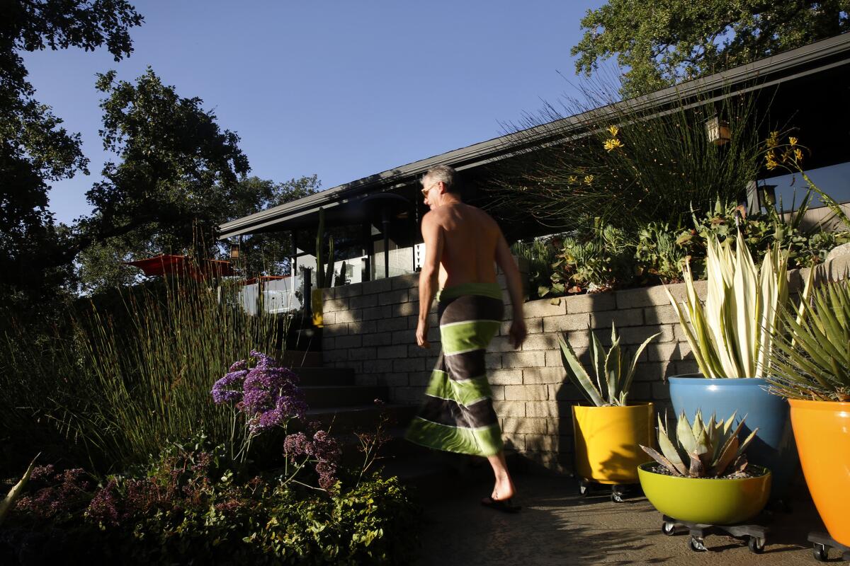 On his way from the pool to his 1950s Pasadena house, Rod Beattie passes by a grouping of ceramic pots in midcentury colors.