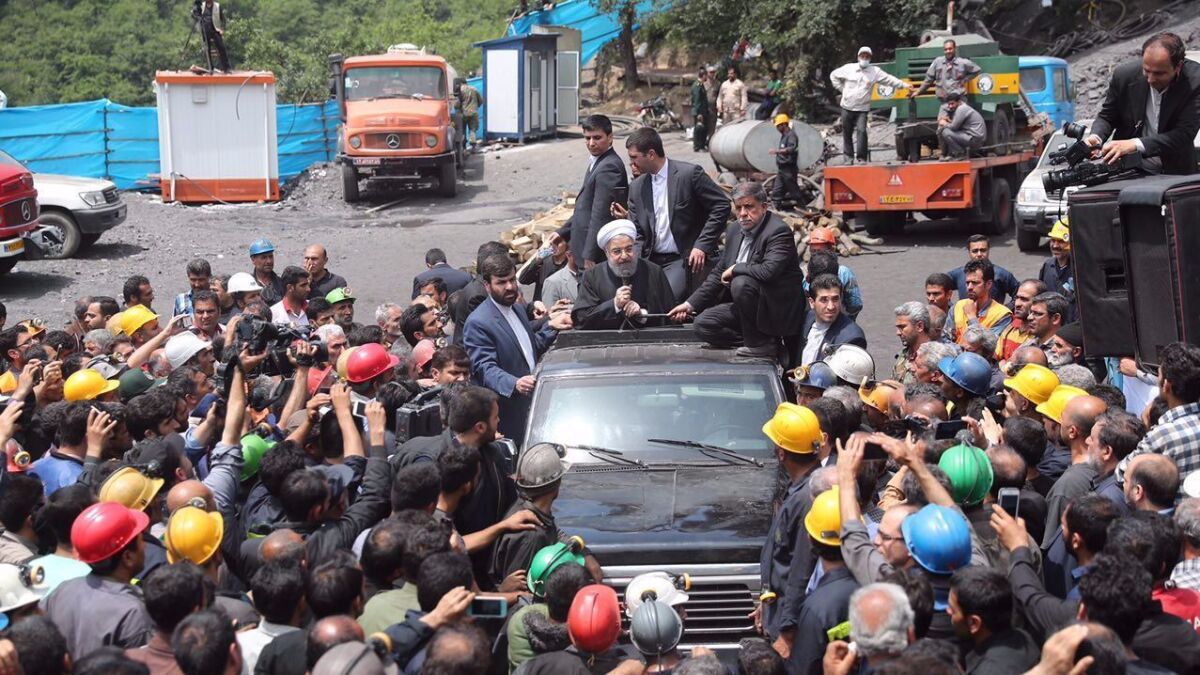 A photo made available by the presidential website shows Iranian President Hassan Rouhani, center, talking with mine workers in the city of Golestan.