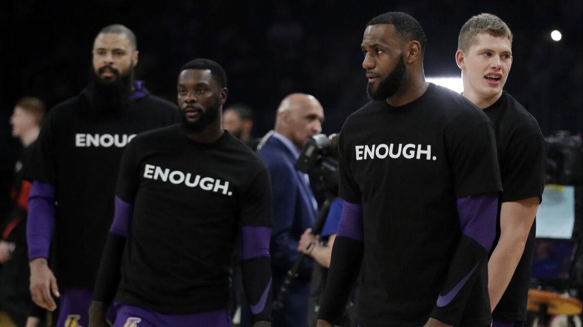 Members of the Los Angeles Lakers, from left, Tyson Chandler, Lance Stephenson, LeBron James and Moritz Wagner wear t-shirts with the word "Enough" in memory of the 12 victims killed in the shooting at a bar in Thousand Oaks.