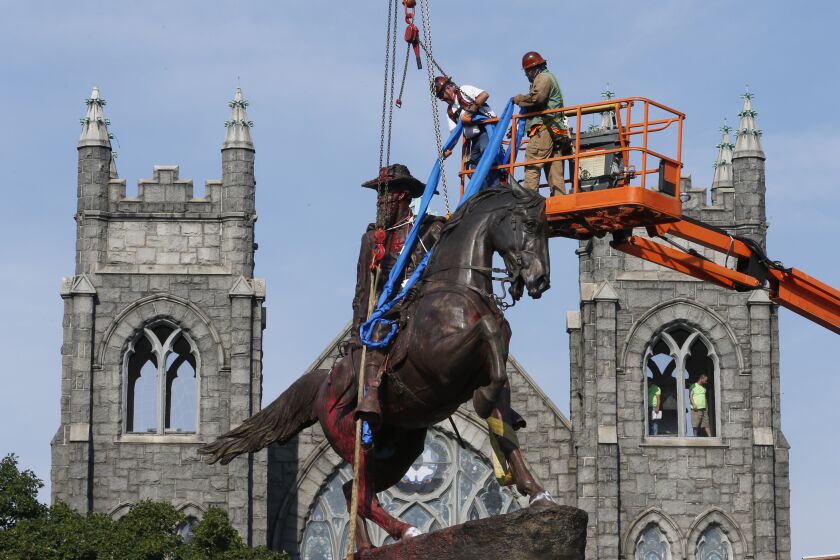 FILE - In this July 7, 2020, file photo, crews attach straps to the statue Confederate General J.E.B. Stuart on Monument Avenue in Richmond, Va. At least 160 Confederate symbols were taken down or moved from public spaces in 2020. That's according to a new count the Southern Poverty Law Center shared with The Associated Press. (AP Photo/Steve Helber, File)