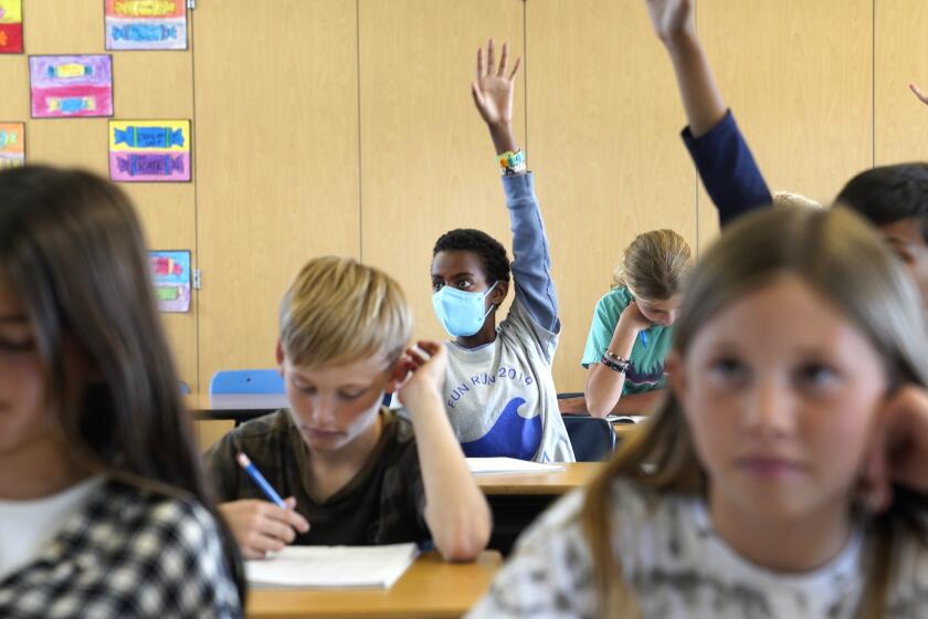 Redondo Beach, California-Hellelujah Borgic, age 11, raises his hand during his 5ht grade class at Tulita Elementary School while in teacher Wendy Demaria's class. Monday March 14 was the first day they are allowed to go maskless. At Tulita Elementary School in Redondo Beach, California students were given the option to attend with or without wearing a masks on March 14, 2022, the first day that that students across Los Angeles County have the option to remove their masks in class. L.A. Unified School District is an exception and students are still required to wear masks. (Carolyn Cole / Los Angeles Times)