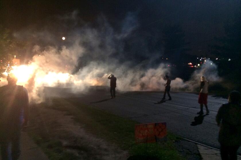 In Ferguson, Mo., on Aug. 11, demonstrators scatter after facing tear gas on a hill.