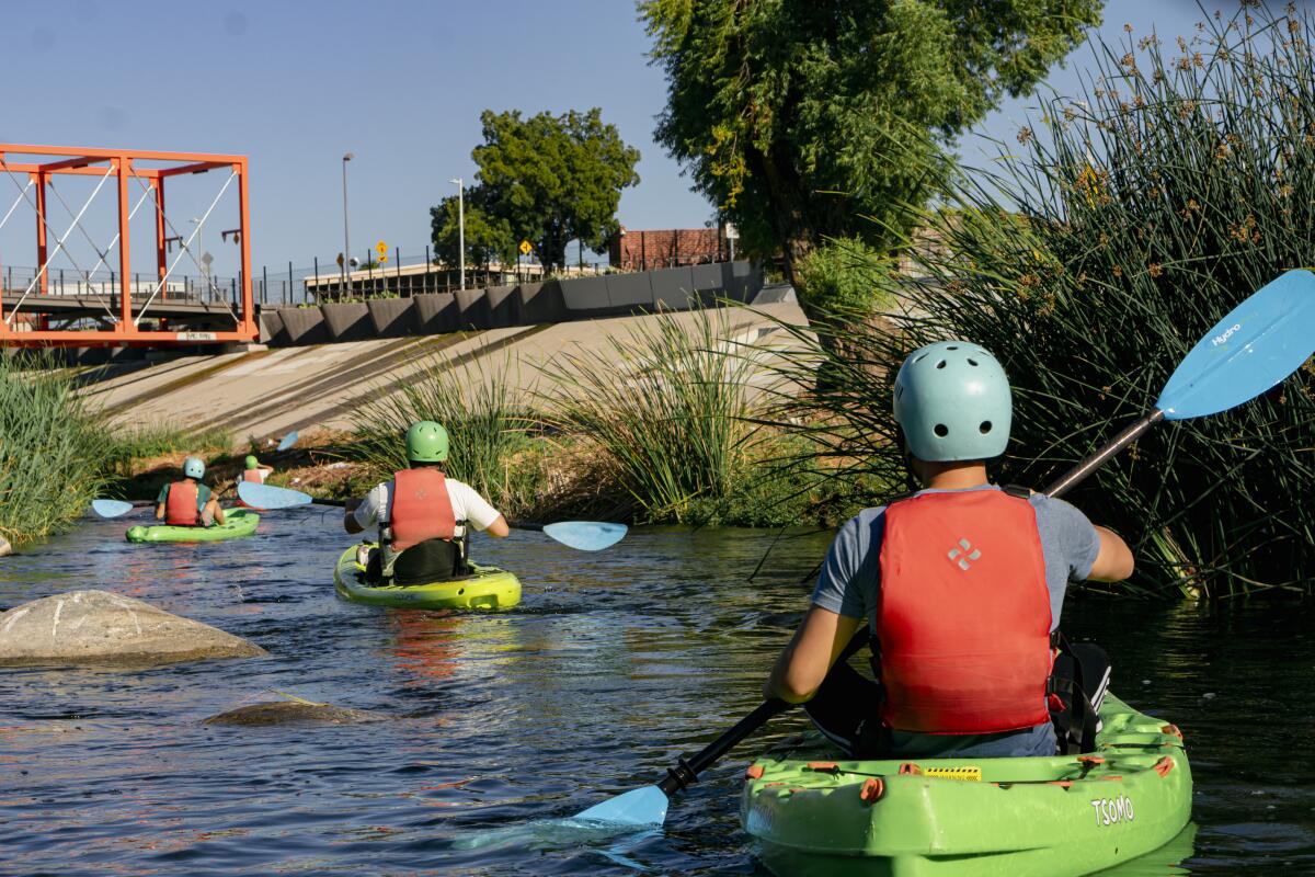 People kayak down a river.