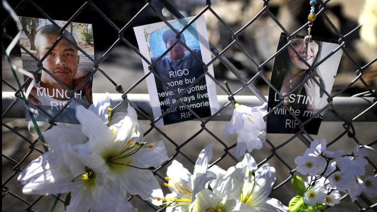 Las fotografías de los tres jóvenes encontrados muertos en una tienda de neumáticos en South El Monte se muestran sobre una valla en la tienda.