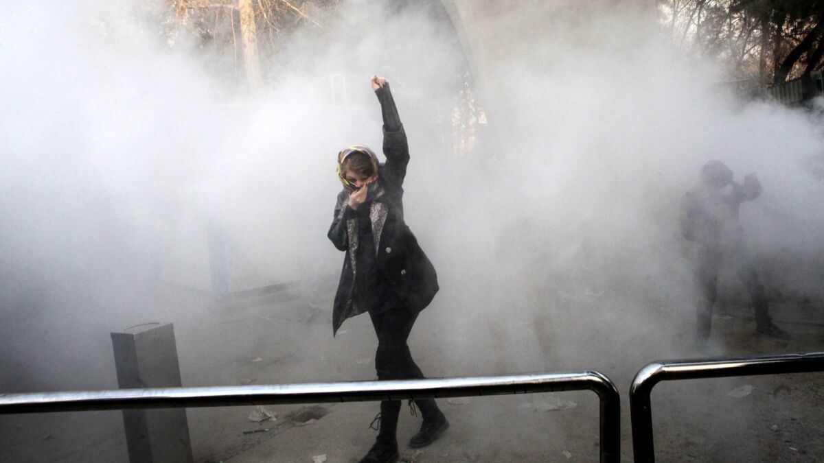 An Iranian woman raises her fist amid the smoke of tear gas at the University of Tehran during a protest driven by anger over economic problems on Dec. 30, 2017.