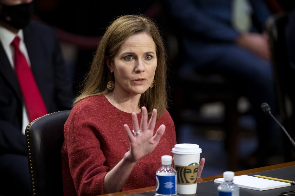 Judge Amy Coney Barrett raises a hand while speaking at a confirmation hearing