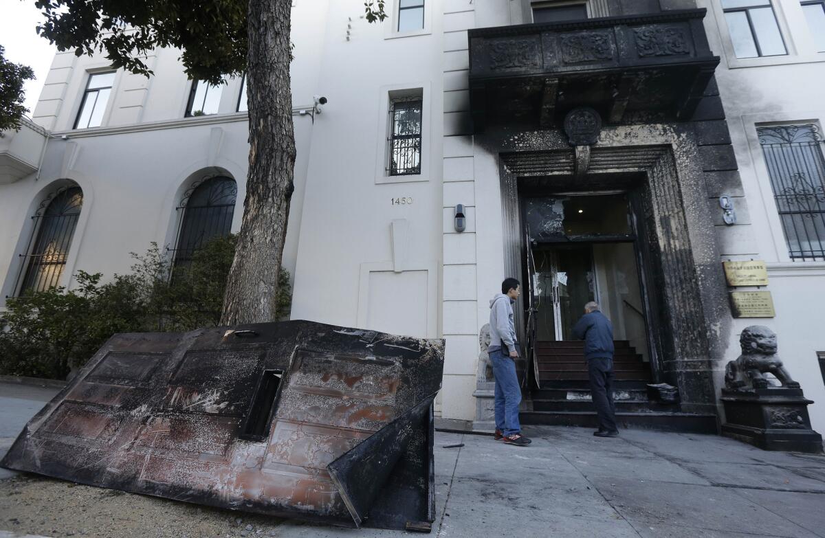 Two men look at damage to the entrance of the Chinese Consulate in San Francisco the day after a fire there.