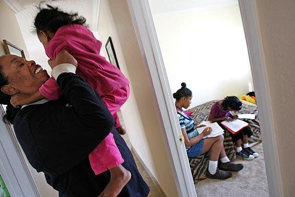 Four-year-old Ronniesha runs to her mother's arms as sisters Lexus, 14, on bed at left, and Ronnique, 9, do their homework.