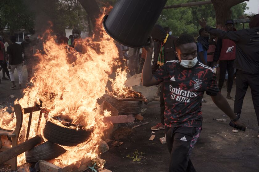 A demonstrator walks past a barricade set on fire during a protest in support of main opposition leader Ousmane Sonko in Dakar, Senegal, Monday, May 29, 2023. The clashes came a day after police stopped Sonko's "freedom caravan," traveling from his hometown of Ziguinchor, in the south and where he is the mayor, to the capital, Dakar, where he was forced into a home he has in the city. (AP Photo/Leo Correa)