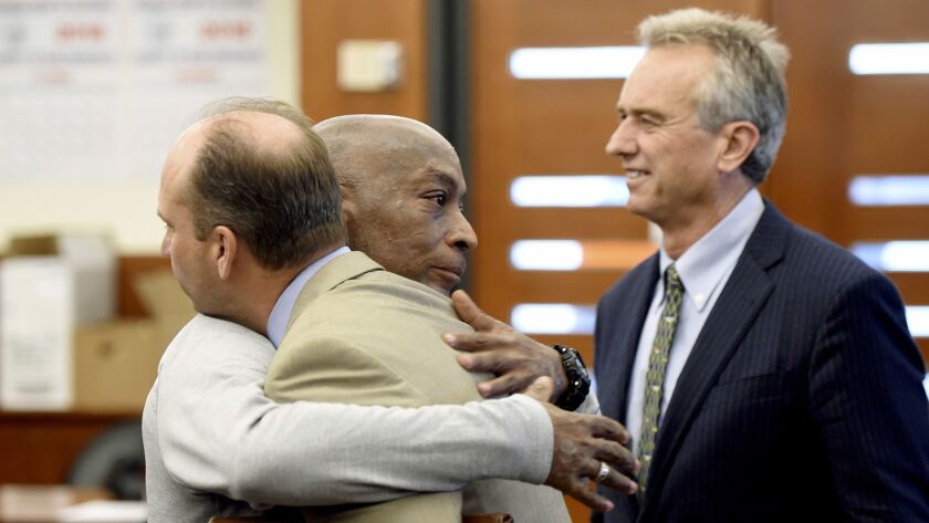 DeWayne Johnson, center, hugs one of his attorneys Friday after winning a $289-million verdict from Monsanto in San Francisco County Superior Court as Robert F. Kennedy Jr., a member of his legal team, looks on.