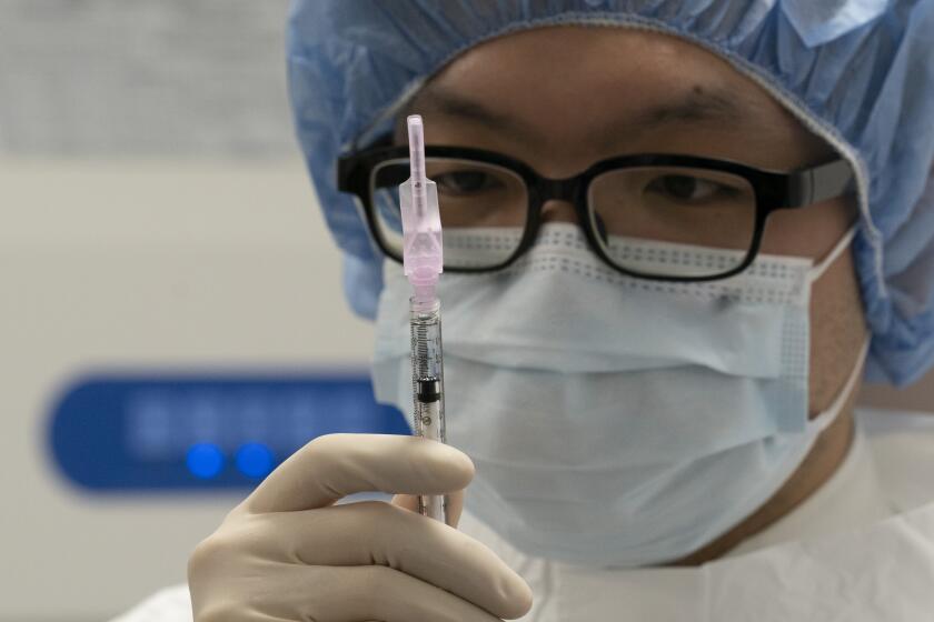 A pharmacist poses with a syringe in a clean room where doses of COVID-19 vaccines will be loaded into syringes, Wednesday, Dec. 9, 2020 at Mount Sinai Queens hospital in New York. The hospital expects to receive thousands of doses once a vaccine is approved. (AP Photo/Mark Lennihan)