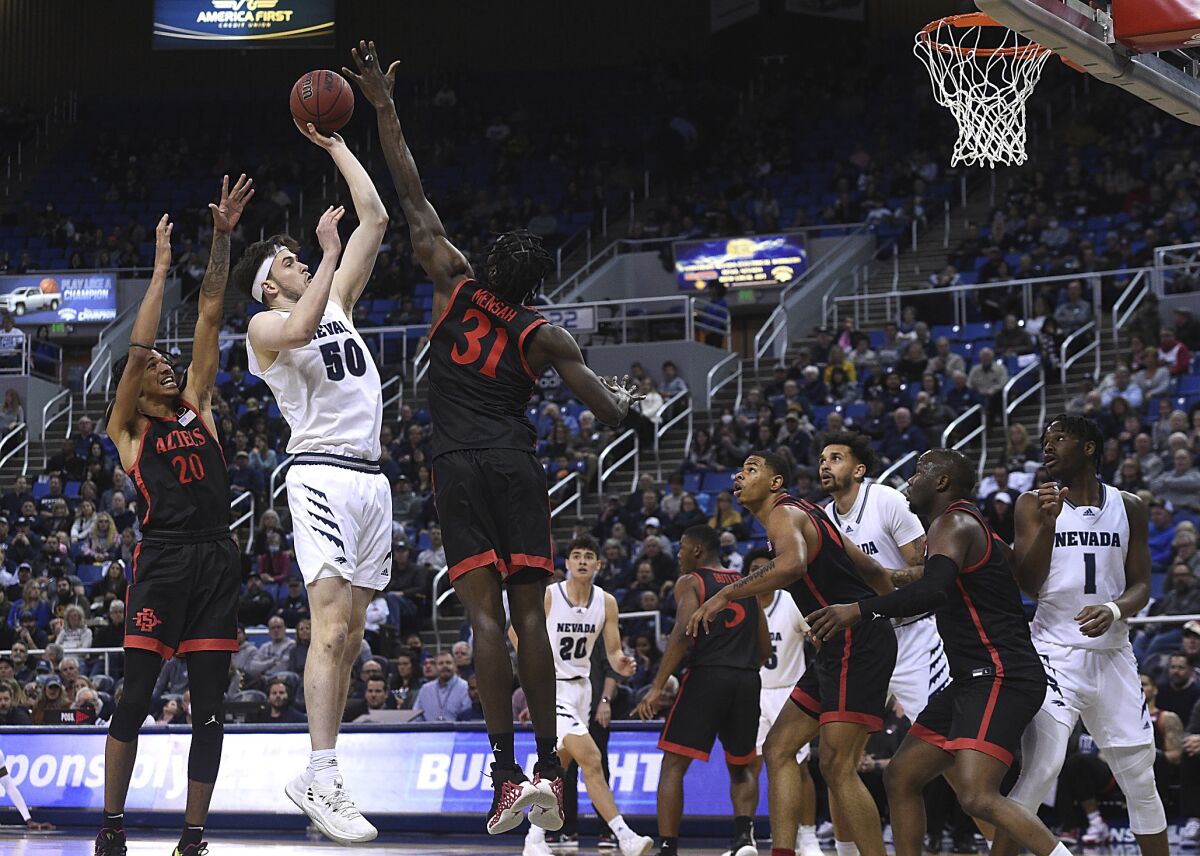 Nevada's Will Baker shoots while being guarded by San Diego State's Nathan Mensah (31) and Chad Baker-Mazara during an NCAA college basketball game Saturday, March 5, 2022, in Reno, Nev. (Jason Bean/The Reno Gazette-Journal via AP)