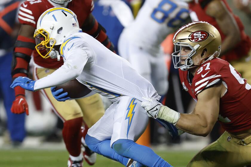 San Francisco 49ers defensive end Nick Bosa, right, tackles Los Angeles Chargers wide receiver DeAndre Carter.