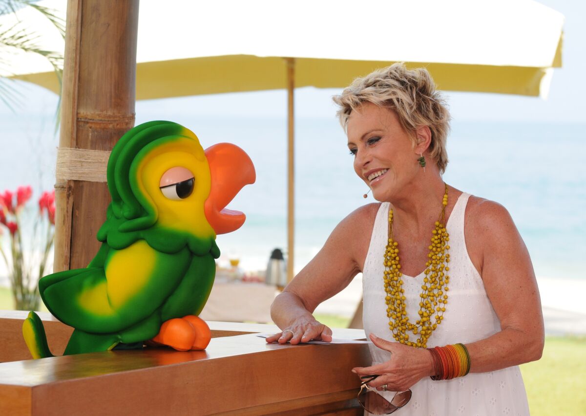 In this photo released on Nov. 2, 2020 by Globo, Globo TV presenter Ana Maria Braga smiles next to the parrot puppet Louro Jose, played by Tom Veiga, in Rio de Janeiro, Brazil. An outpouring of emotion in Brazil has followed news that the puppeteer behind Louro José, a two-foot-tall parrot that’s a fixture on the country’s most popular morning show, had passed away. (Globo via AP)