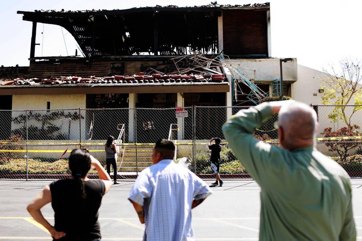People gather to look at the remains of St. John Vianney Church in Hacienda Heights on April 17, 2011, a day after it was set ablaze.