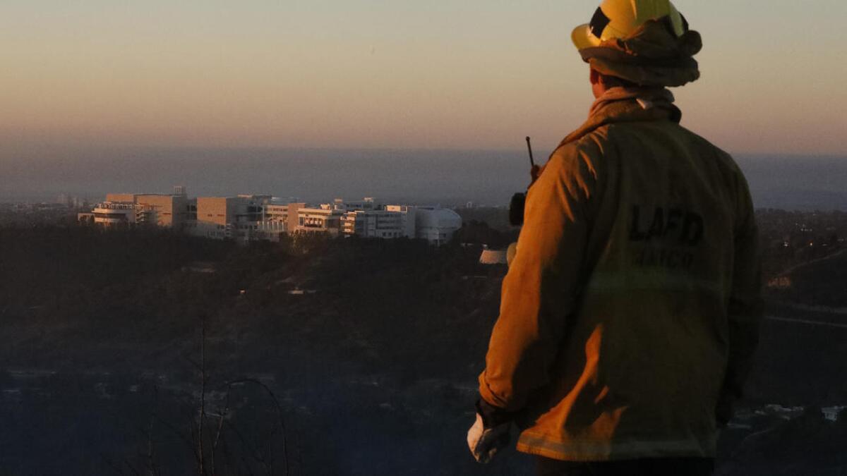 Firefighter Bobby D'Amico looks out over the Getty Center while monitoring the scene over Bel-Air.