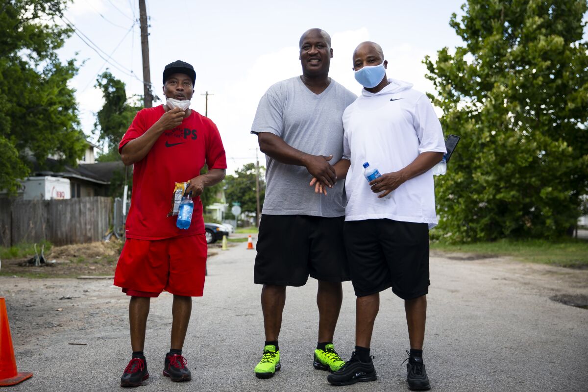 Friends of George Floyd greet one another across the street from his mural in the Third Ward in Houston.