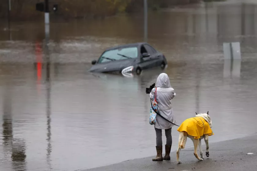 Fanny Santosa walks her dog Enzo along the flooded Mission Center Road near in Mission Valley on January 16.