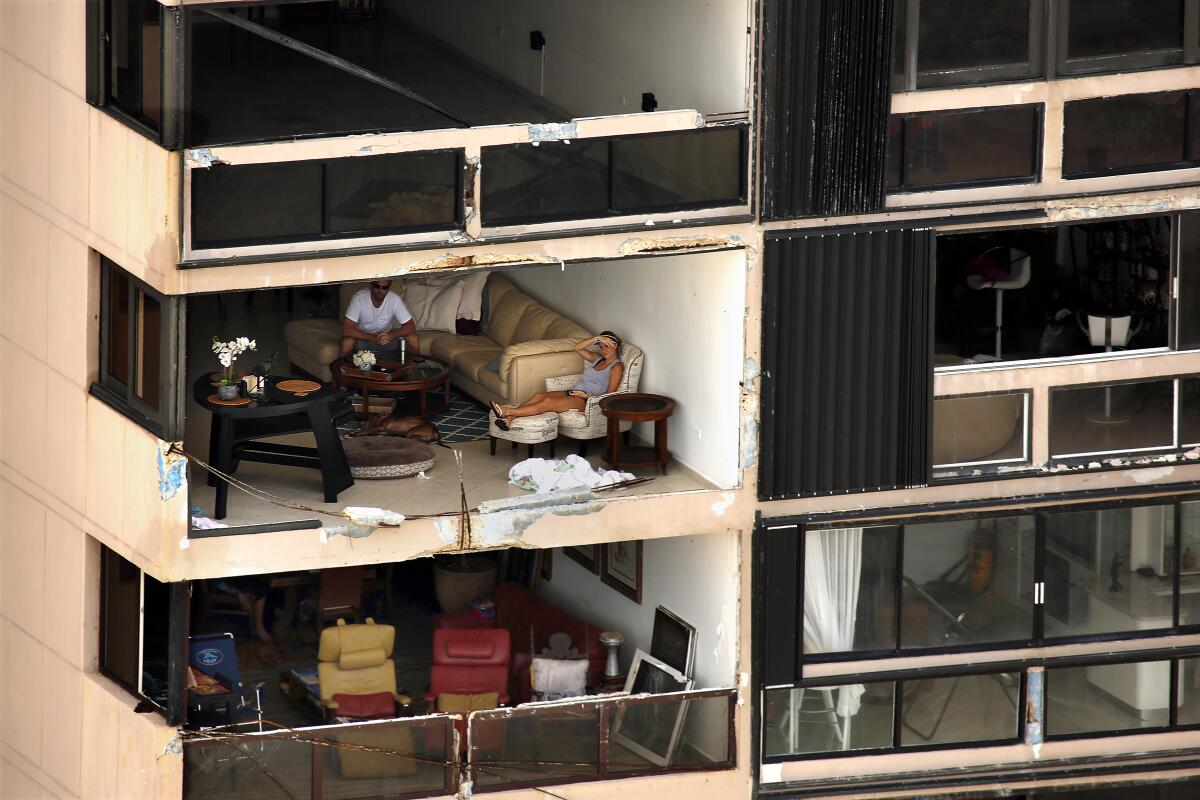 People sit in a San Juan, Puerto Rico, apartment with exterior walls missing after Hurricane Maria.