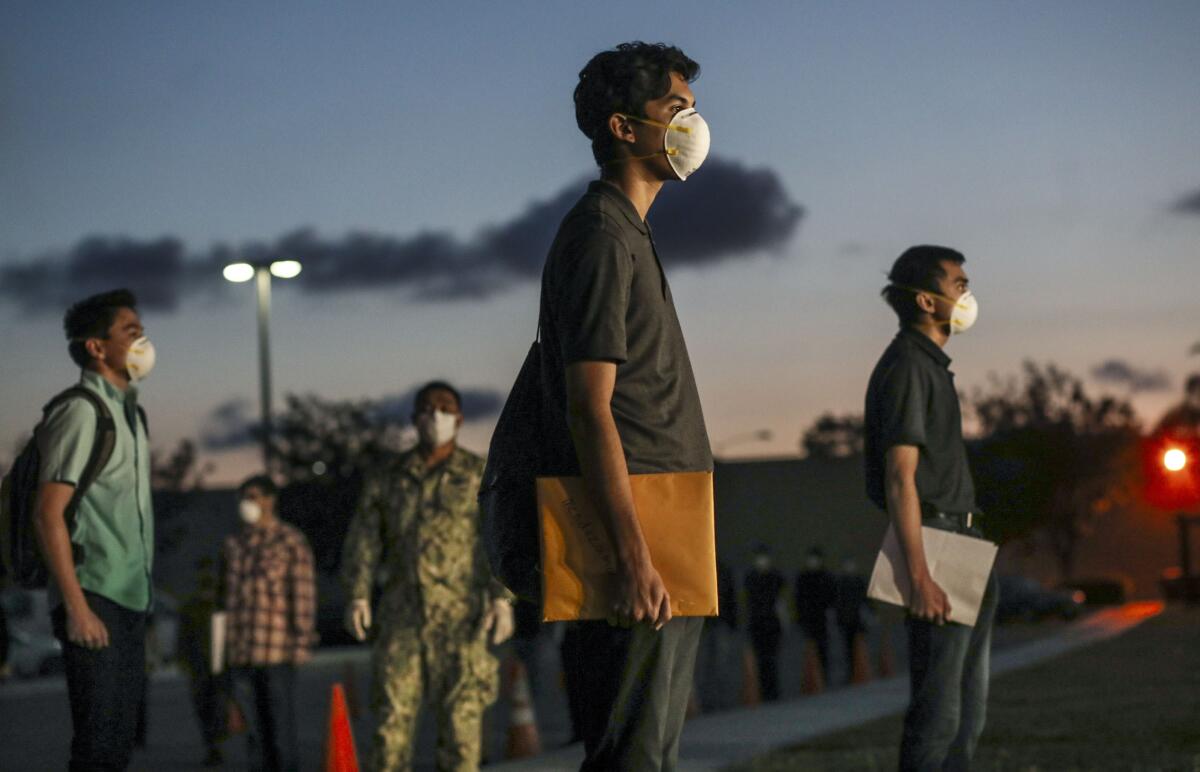 Marine recruits stand in formation as they await health screenings at the Marine Corps Recruit Depot in San Diego on April 13. New coronavirus distancing practices went into effect such as standing six feet apart, health screenings and a 14-day quarantine period before boot camp begins.