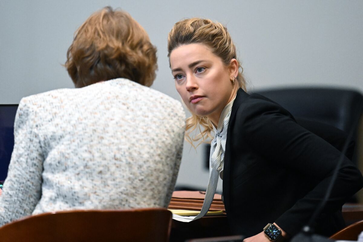 A woman listens intently to her female attorney in a courtroom